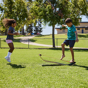 Two children playing with a slackboard in a park on a sunny day.