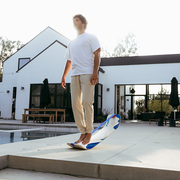 Person standing on a blue and white mountain slackboard in front of a modern house.