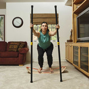 Woman using two balance poles while squating on a sunbeam slackboard in a living room.