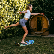 Person riding a waves slackboard plus in a garden with a wooden barrel in the background